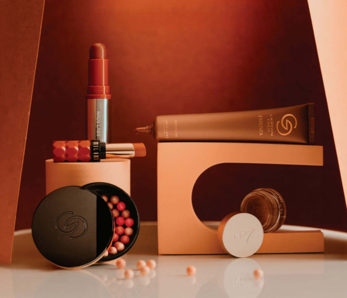 A still life style image of bronzing makeup products against a brown background.